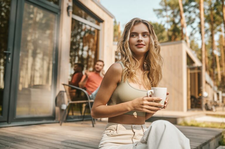 Woman with cup sitting on porch of house
